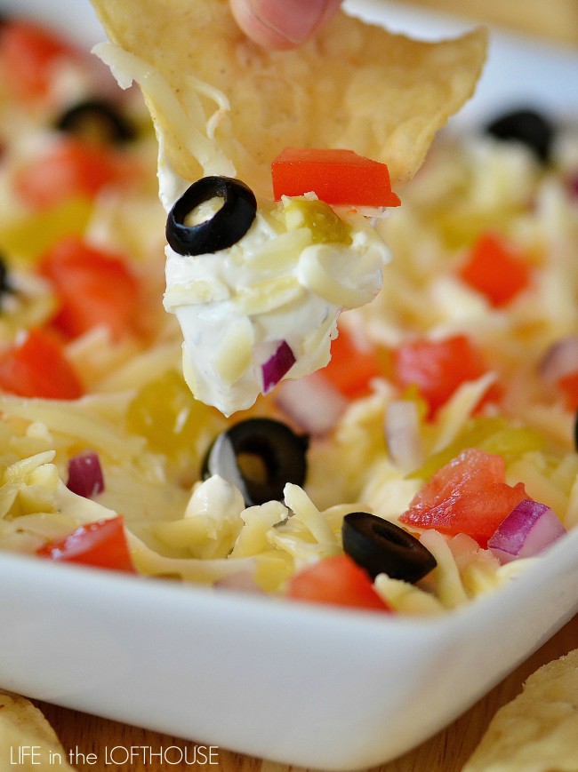 This dip has a thick and creamy layer of sour cream that's been flavored with ranch seasoning, and topped with shredded Monterey Jack cheese, diced green chilies, tomatoes and olives. Life-in-the-Lofthouse.com