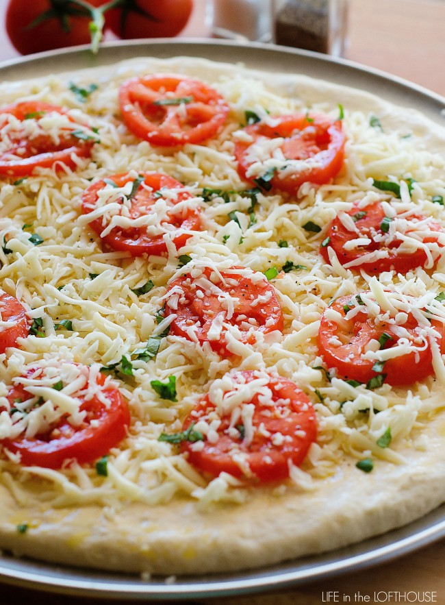 This Margherita Pizza has all the essentials- olive oil, garlic, tomato, freshly grated Mozzarella cheese and basil leaves on top of homemade pizza dough. Life-in-the-Lofthouse.com