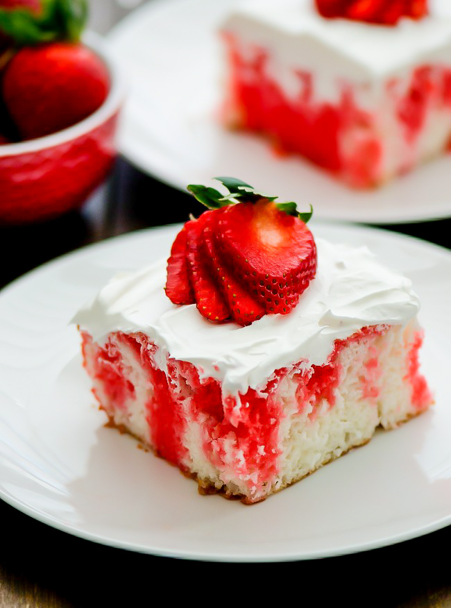 Incredibly light and delicious Strawberry Jello Poke Cake! This white cake is filled with strawberry jello and topped with fresh whipped cream and strawberries.