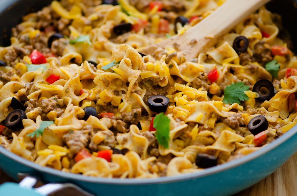 A delicious skillet with noodles, ground beef, olives and red bell peppers with taco seasonings. Life-in-the-Lofthouse.com