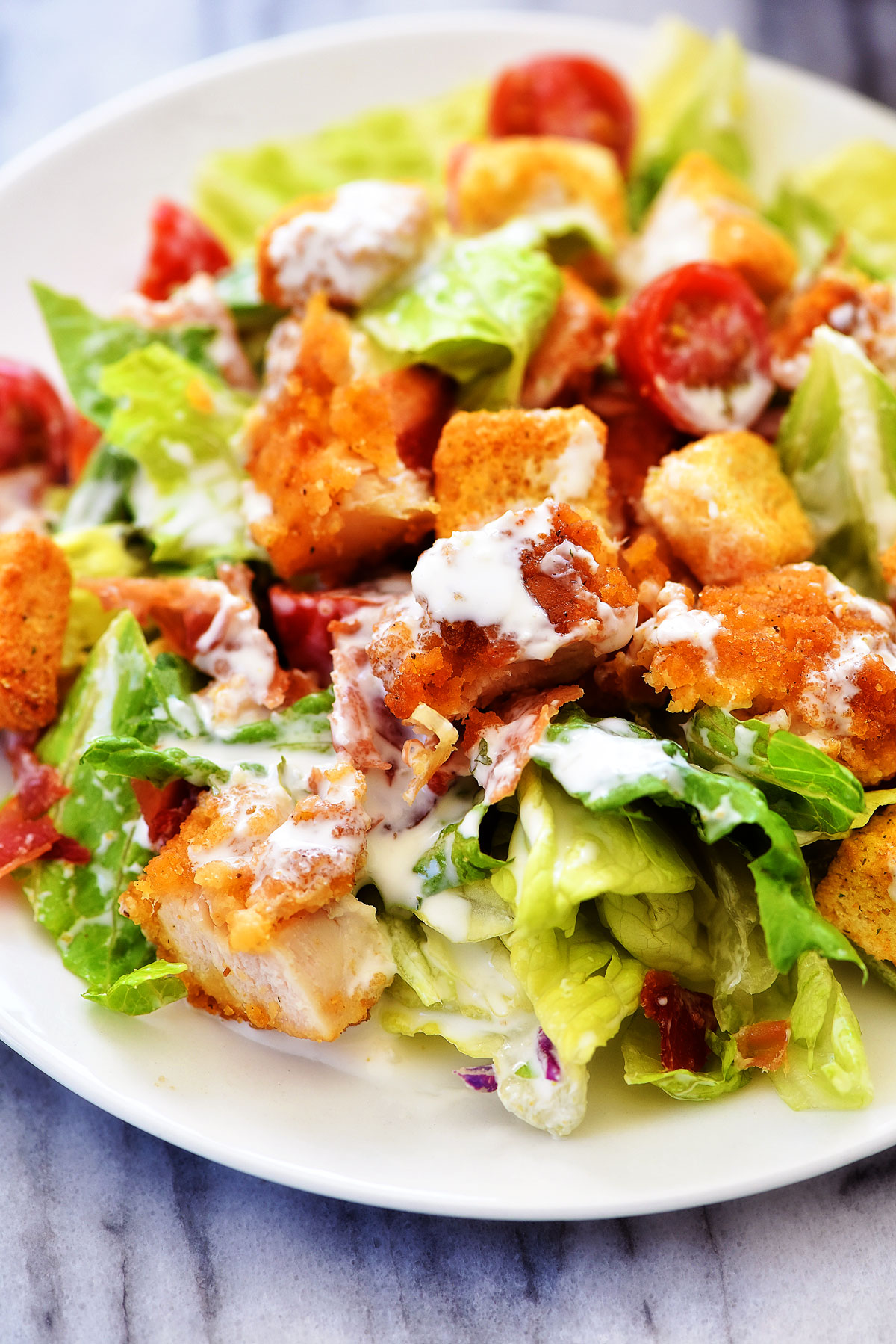 Crispy Chicken BLT Salad is loaded with chicken tenders, lots of chopped bacon, cherry tomatoes and croutons over a bed of romaine lettuce. Life-in-the-Lofthouse.com