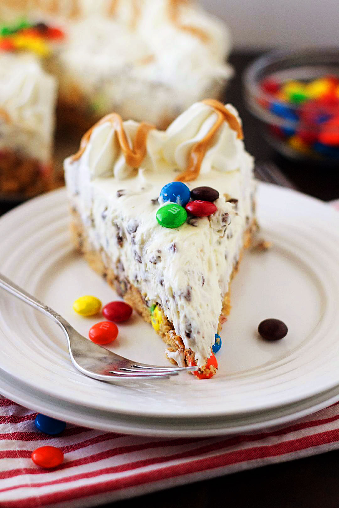Monster Cookie Dough Cheesecake has a crust that is a monster cookie dough loaded with M&M’s and mini chocolate chips and topped with a creamy cheesecake filling loaded with mini chocolate chips. Life-in-the-Lofthouse.com