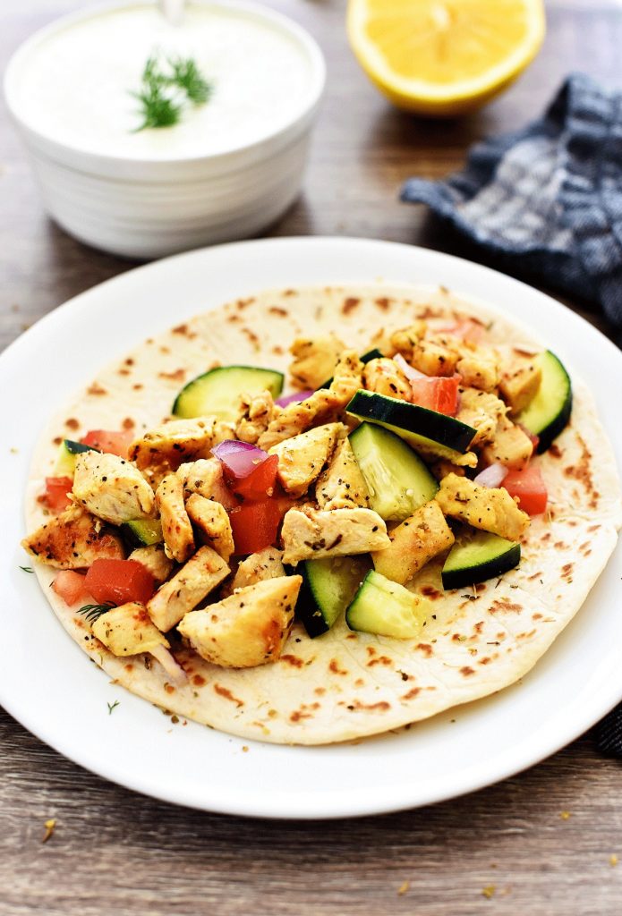 Greek Chicken Wraps are loaded with veggies, seasoned grilled chicken and Tzatziki sauce all wrapped inside a warm flatbread. Life-in-the-Lofthouse.com