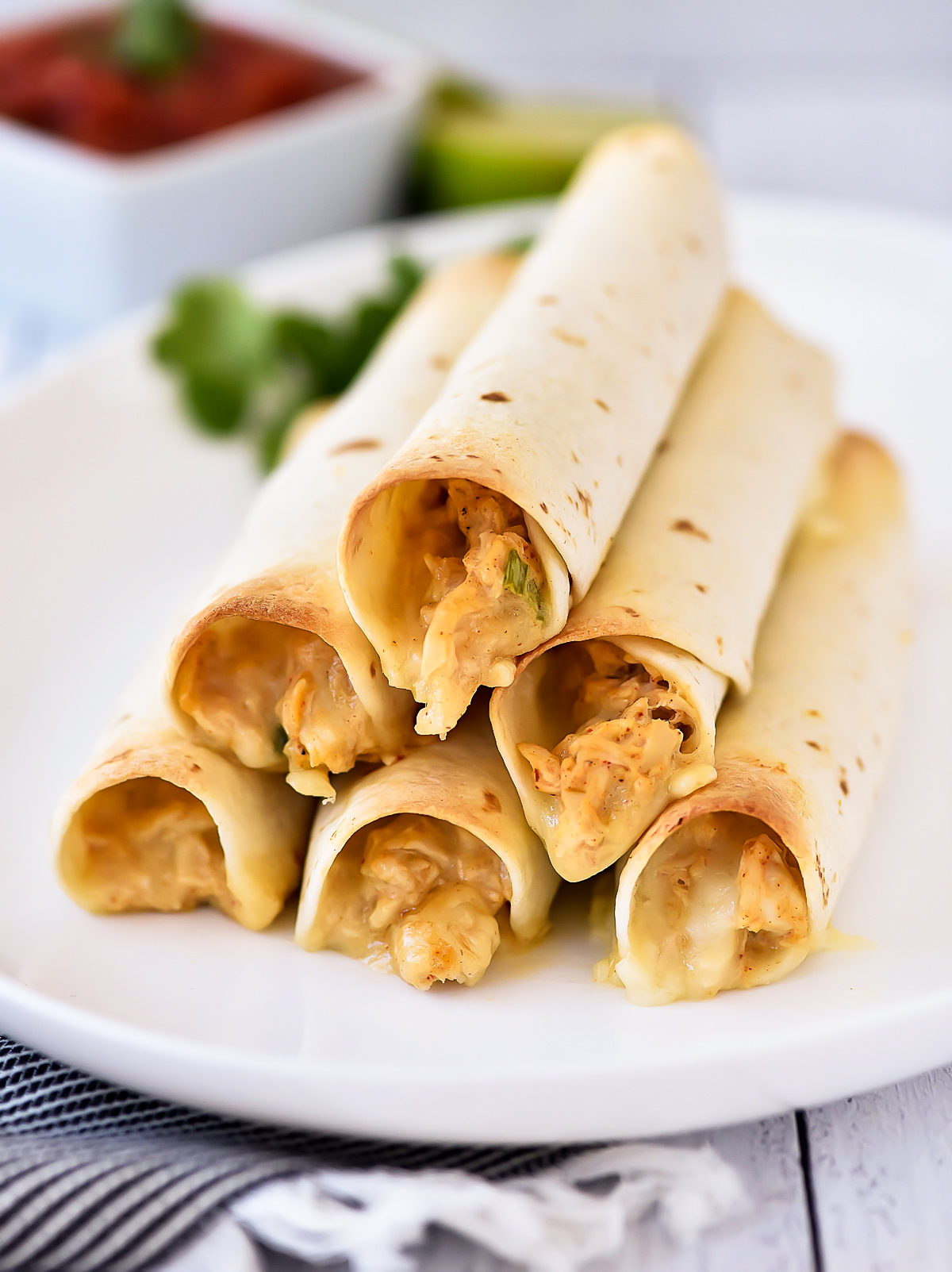 Baked Chicken Taquitos are a crispy flour tortilla wrapped around a warm center of creamy and cheesy Mexican chicken.