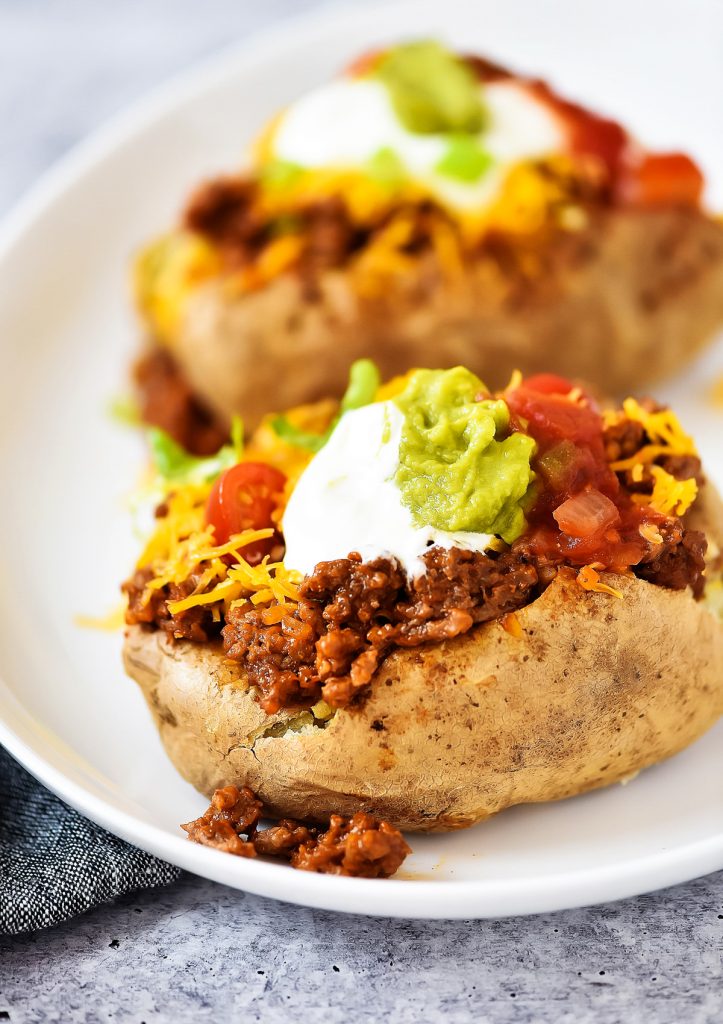 Taco Potatoes are loaded with seasoned ground beef, cheese, lettuce, sour cream and salsa all over a baked potato. Life-in-the-Lofthouse.com