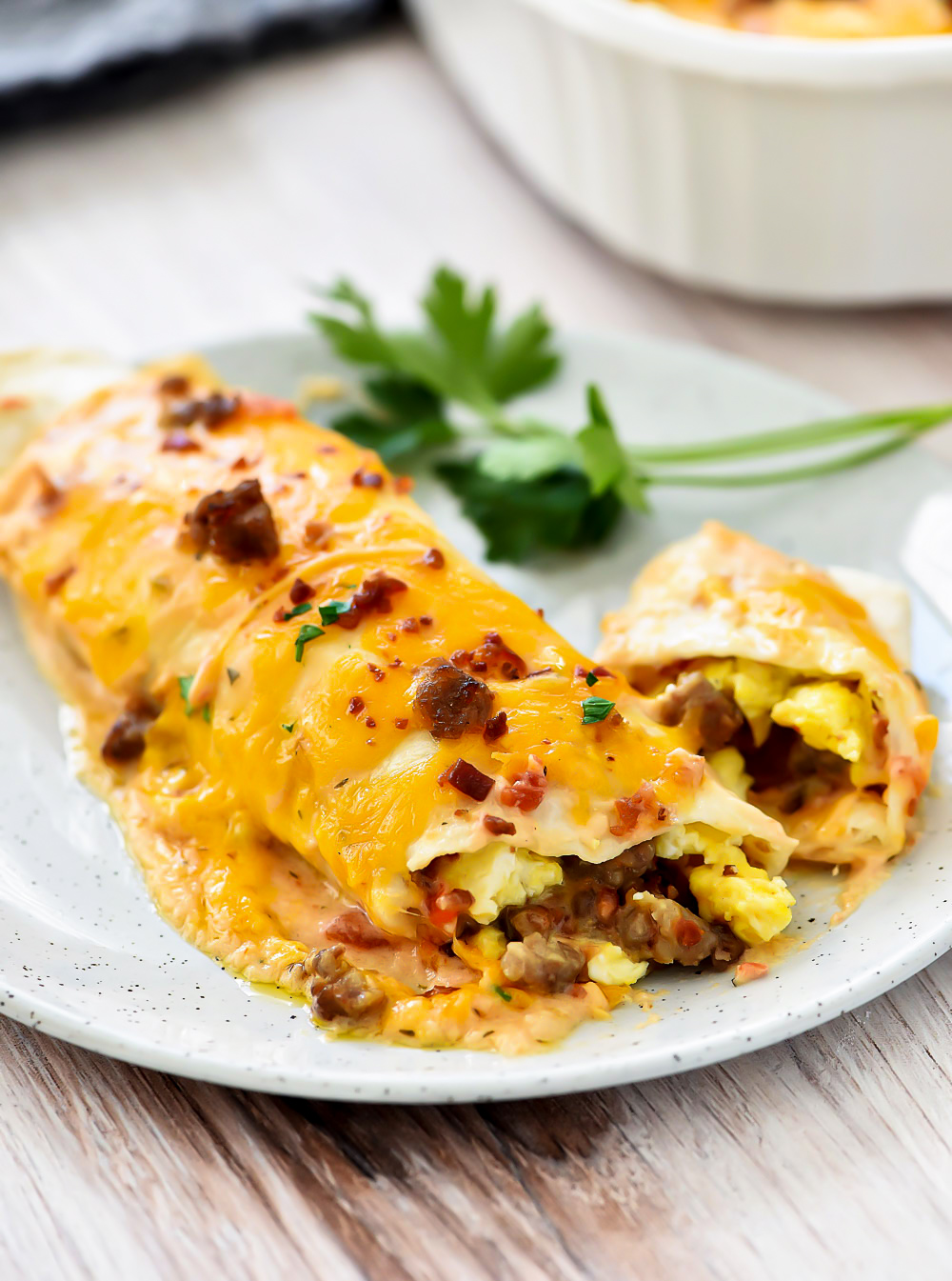 Breakfast Enchiladas are filled with eggs, bacon, sausage and cheese covered in flour tortillas and enchilada salsa. Life-in-the-Lofthouse.com