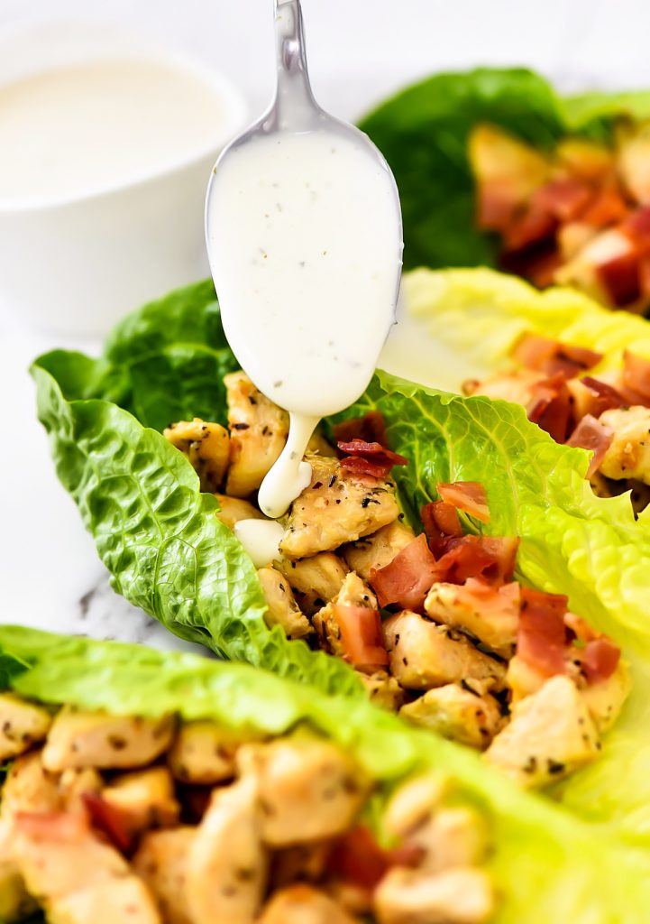 Seasoned chicken and crumbled bacon are filled inside of romaine lettuce leaves. They are topped off with ranch dressing.