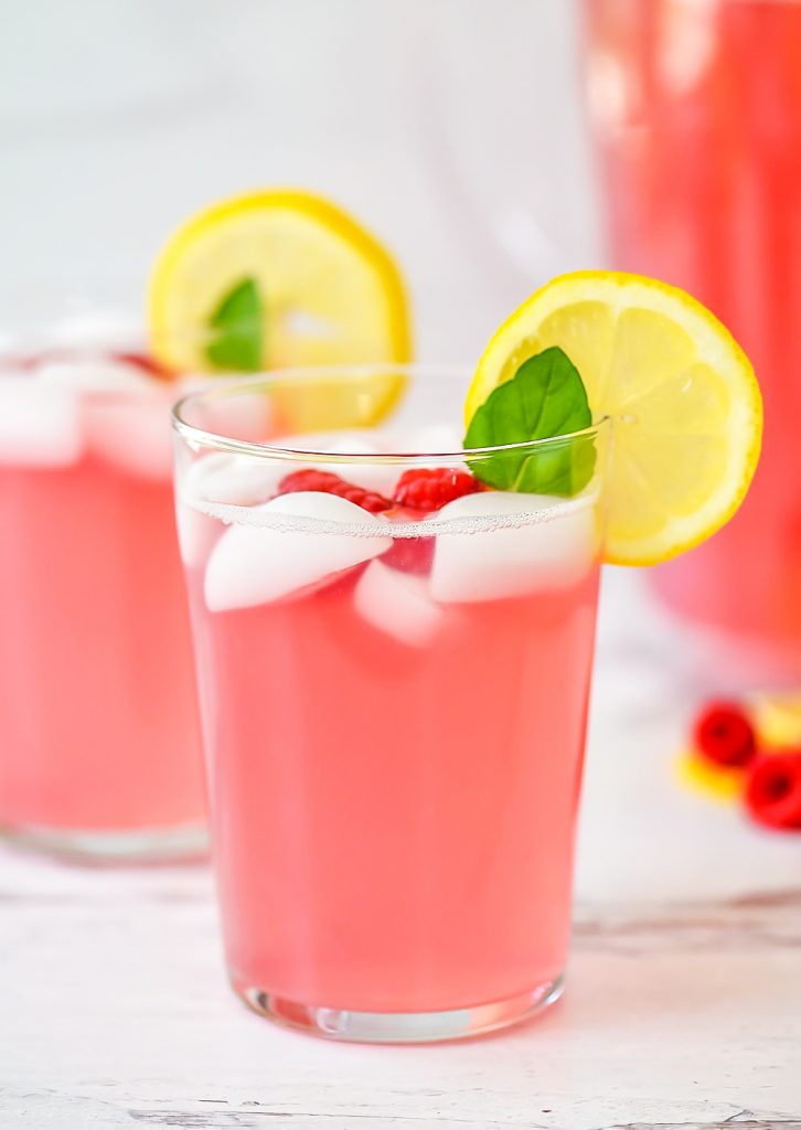 Lemonade with raspberry flavor. Garnished with raspberries, lemon and mint leaves.