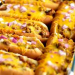 Oven-baked Chili Cheese dogs are loaded hot dogs with chili, cheese and onion, baked in the oven. Life-in-the-Lofthouse.com