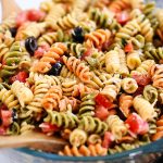 Tri Color Pasta Salad is filled with noodles, fresh veggies, and Parmesan cheese. It’s tossed in a creamy Caesar dressing and basil pesto