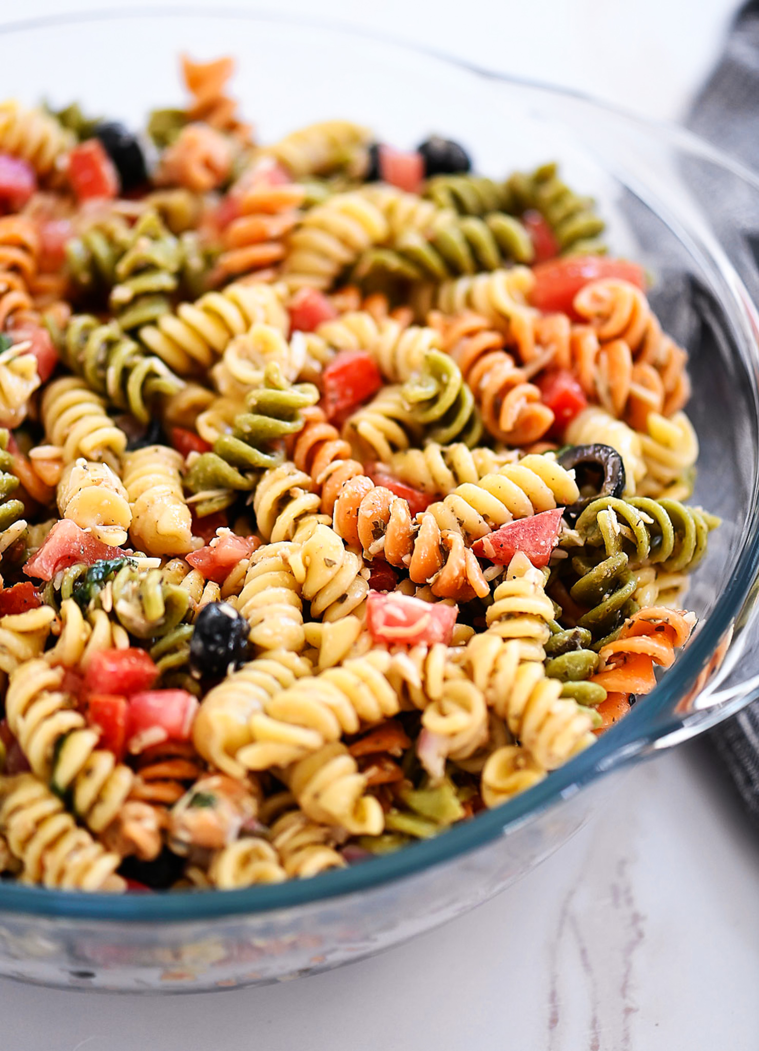 Tri Color Pasta Salad is filled with noodles, fresh veggies, and Parmesan cheese. It’s tossed in a creamy Caesar dressing and basil pesto