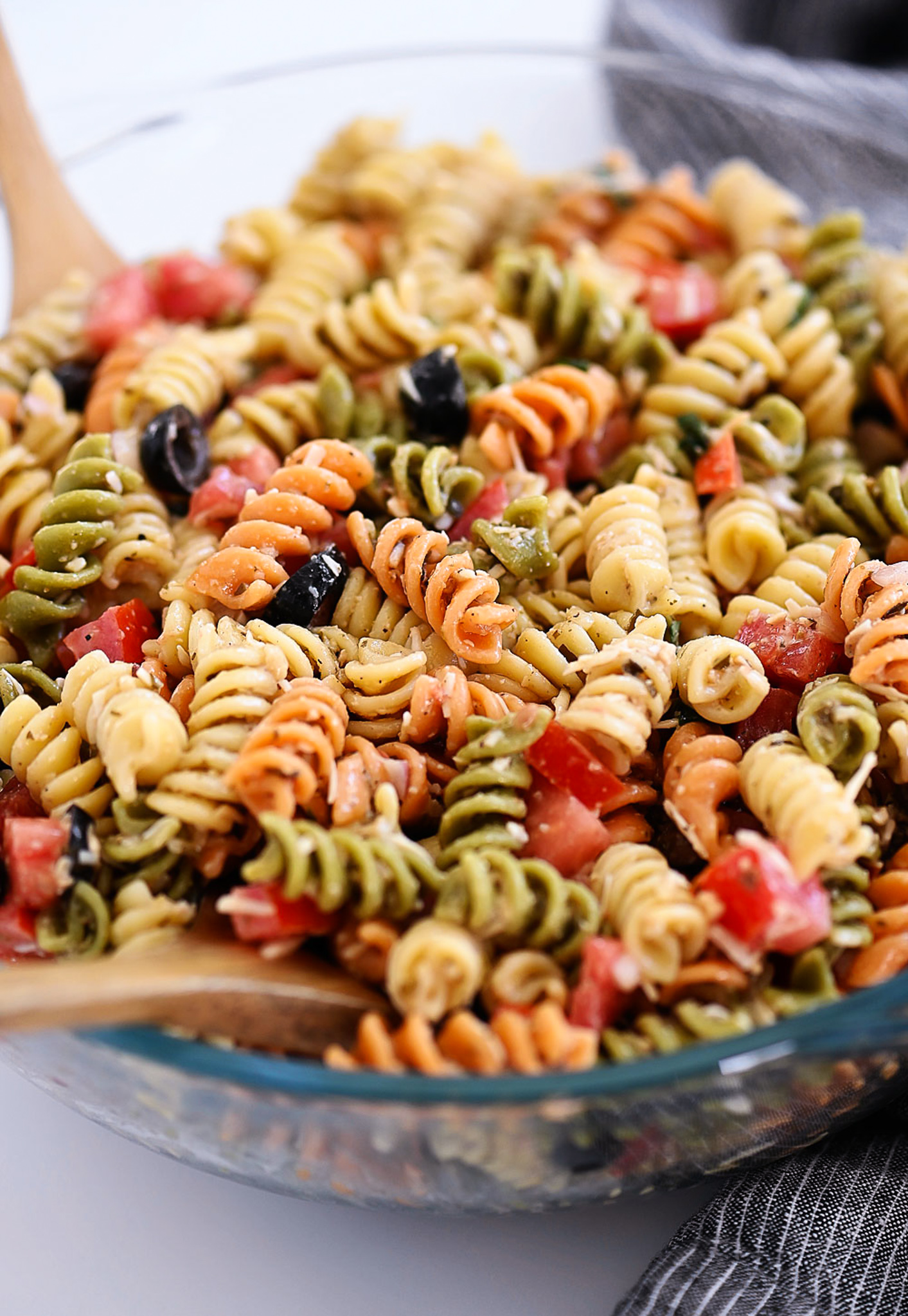 Tri Color Pasta Salad is filled with noodles, fresh veggies, and Parmesan cheese. It’s tossed in a creamy Caesar dressing and basil pesto for one flavor-packed dish.