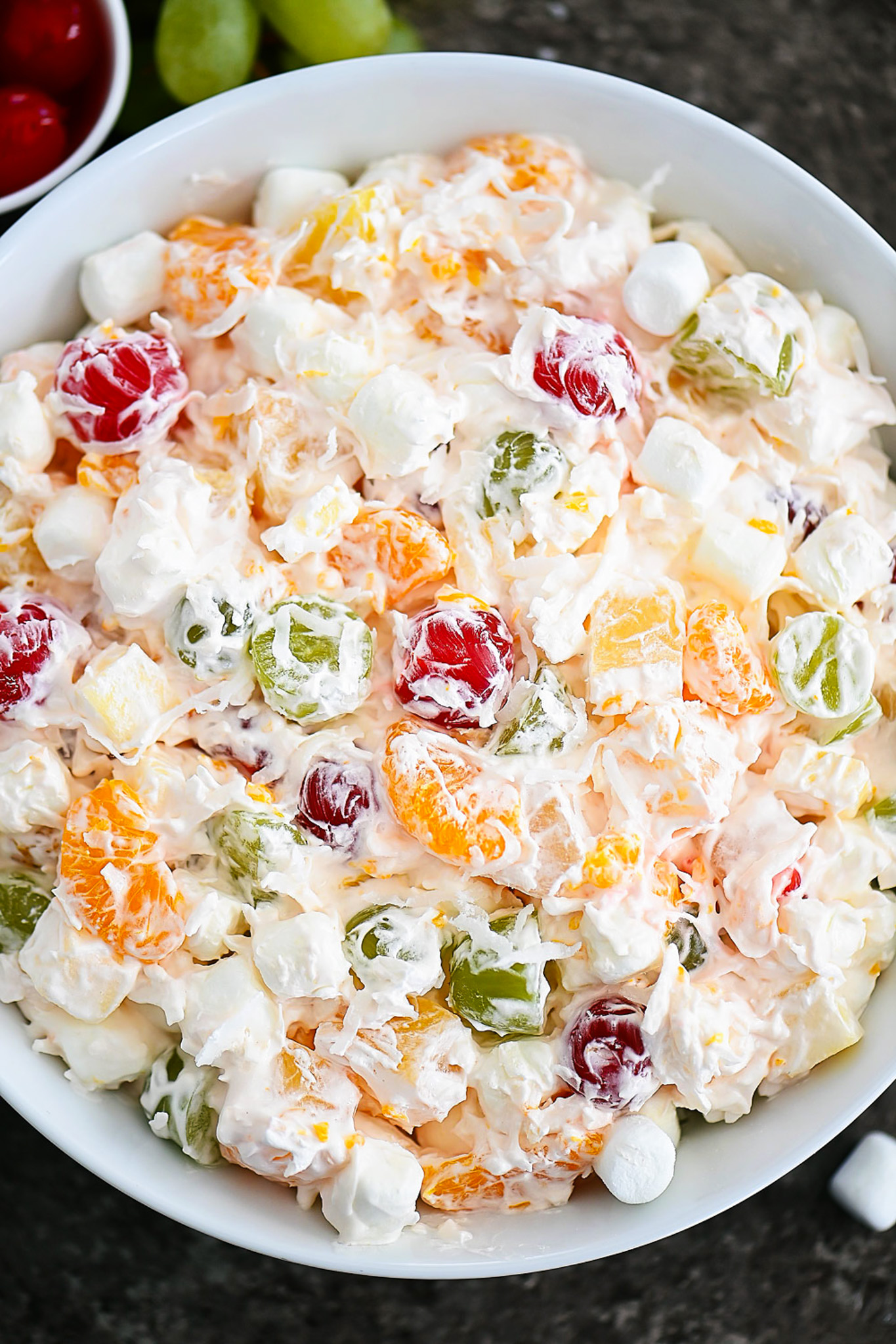 Ambrosia salad has apples, oranges, pineapples and grapes all tossed together in whipped topping and shredded coconut. Life-in-the-Lofthouse.com