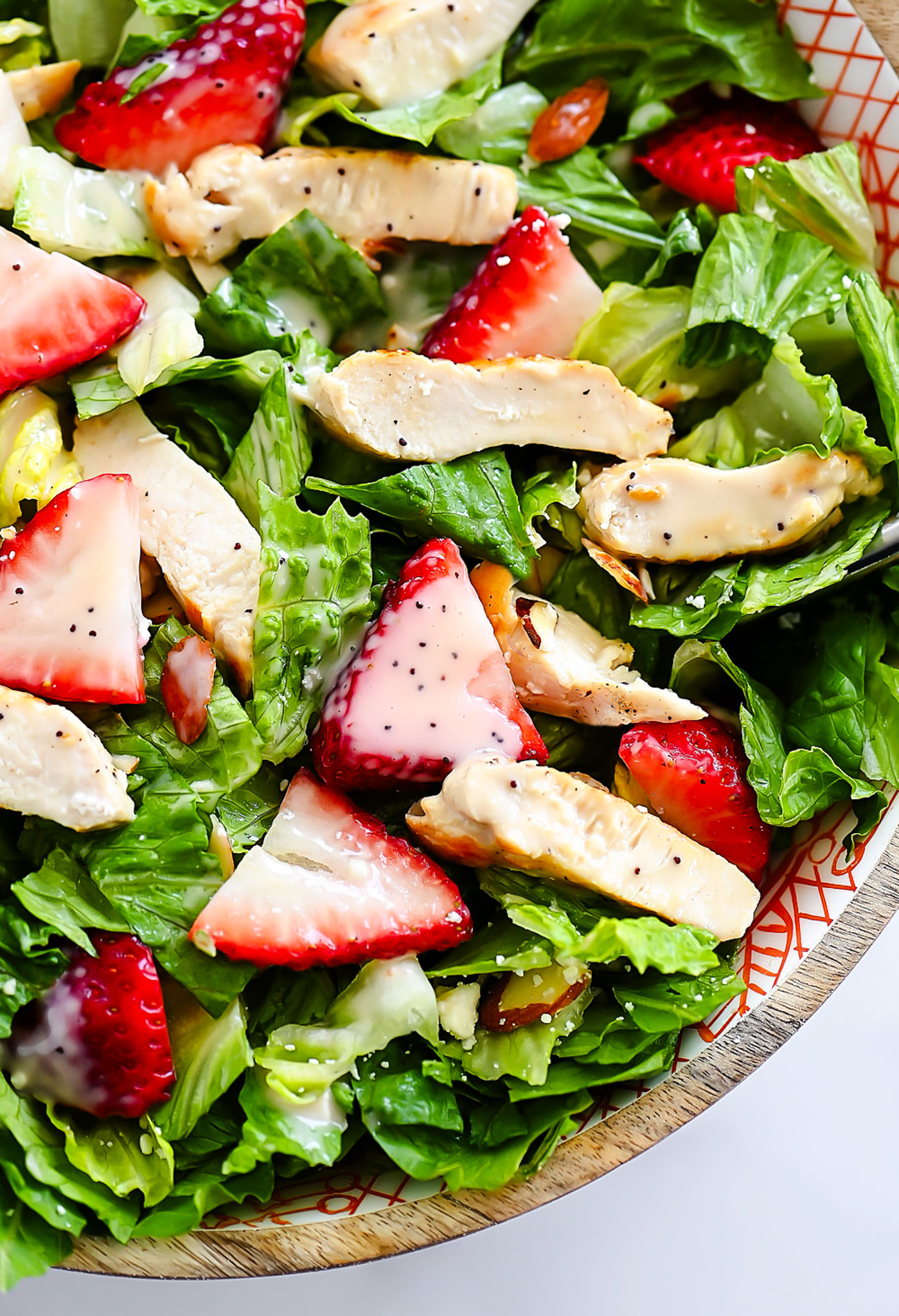 Strawberry Chicken Salad is filled with chopped romaine lettuce, sprinkles of sliced almonds, sliced strawberries and grilled chicken.