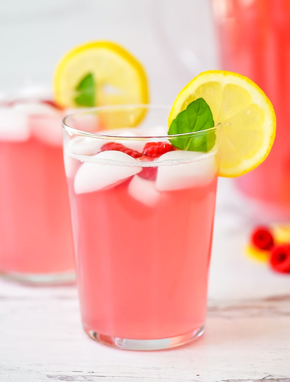 Lemonade with raspberry flavor. Garnished with raspberries, lemon and mint leaves.